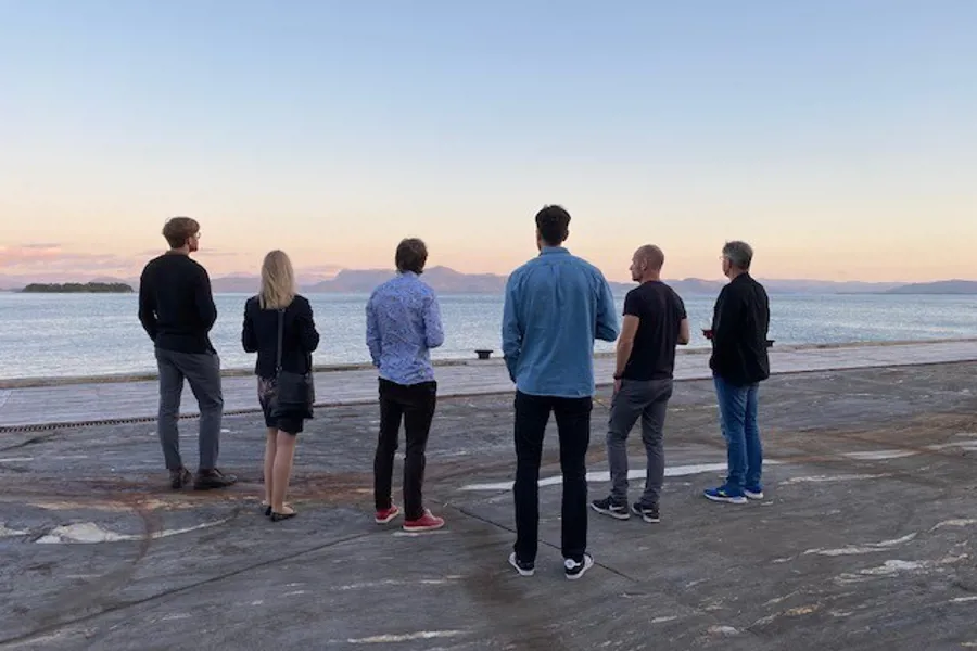 En gruppe mennesker som står på en strand og ser på vannet