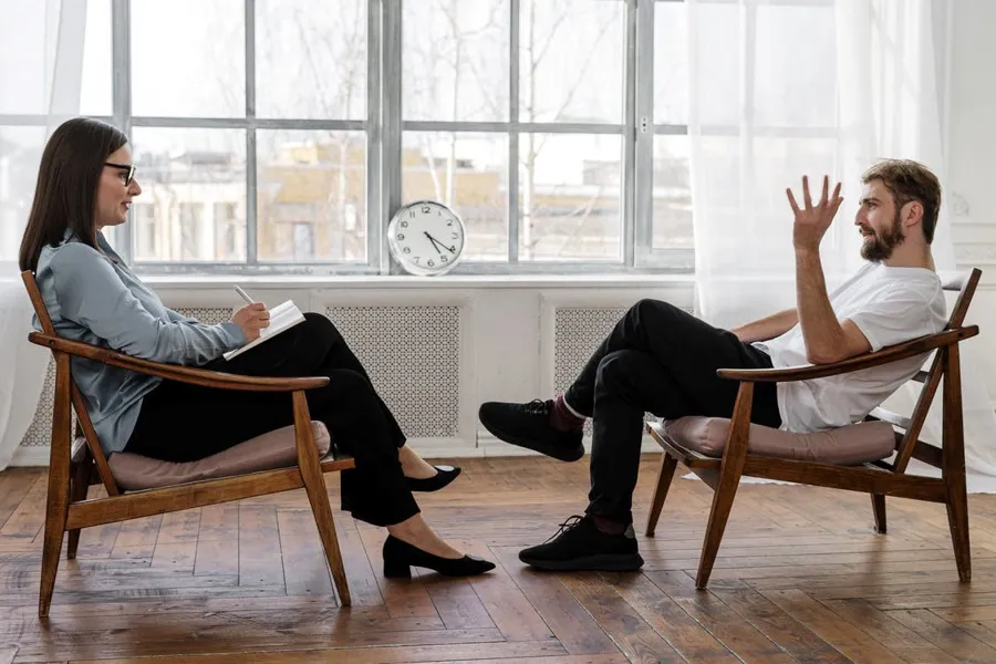 En mann og en kvinne som sitter i stoler i et rom med klokke